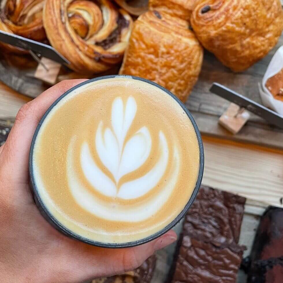 A rosetta latte art pour at Kahaila, with pastries on the counter